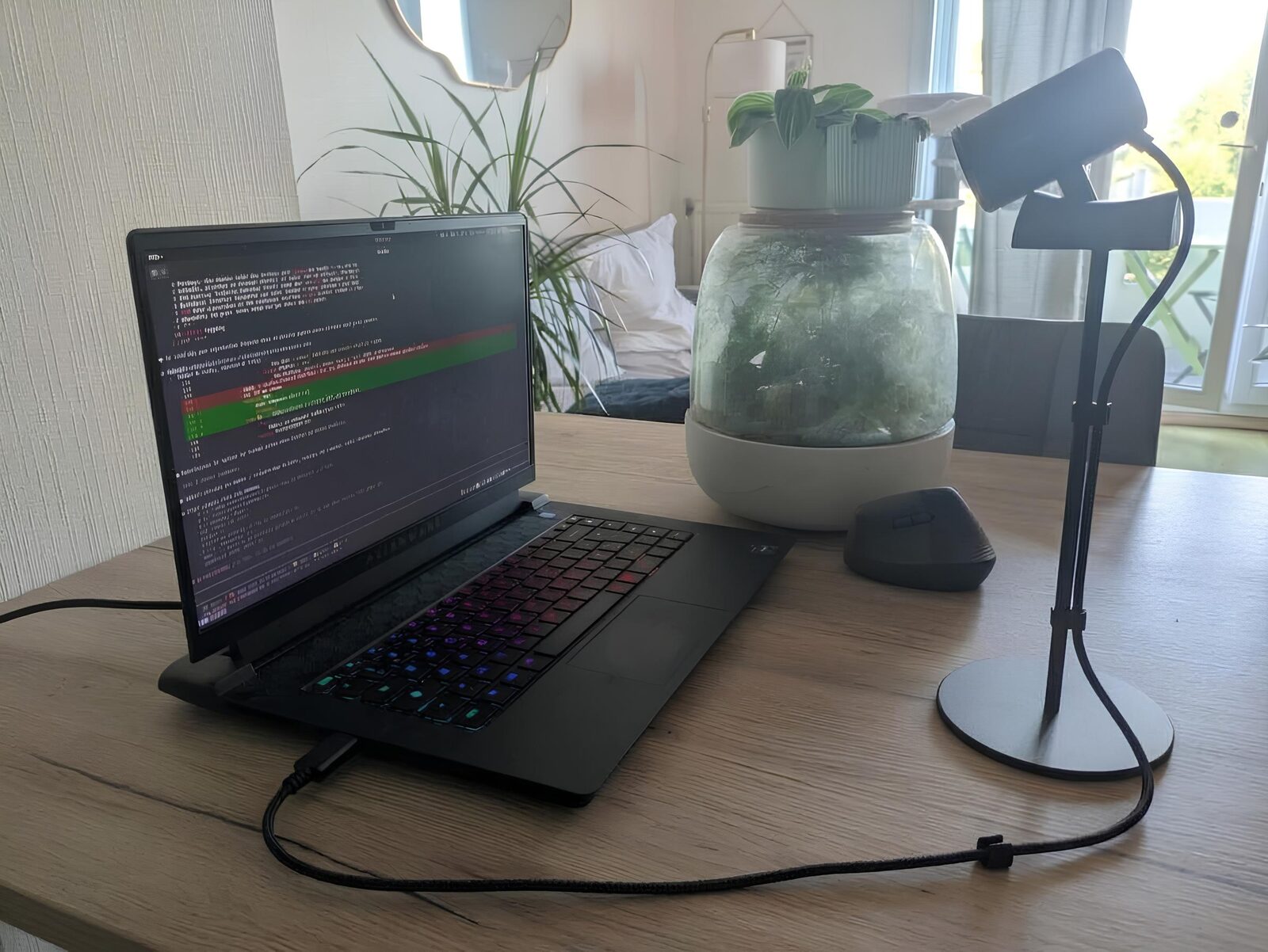 The Alienware m15 R7 on a table, keyboard lit, with a Logitech C920 on a stand beside it, aimed at the keyboard
